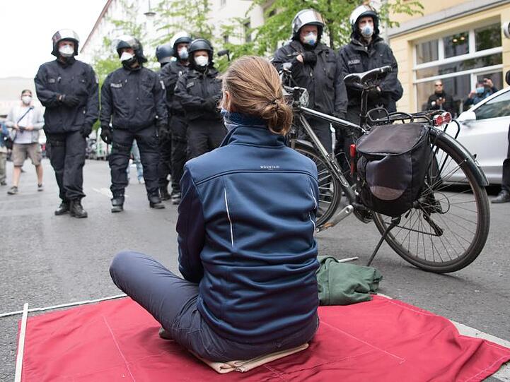 Eine Teilnehmerin sitzt bei der Kundgebung in Berlin-Mitte auf einer mitgebrachten Decke.