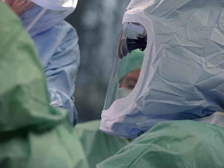 Ein Mediziner-Team trägt Schutzkleidung während der Operation. Foto: picture alliance / dpa/Archivbild