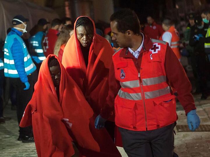 Afrikanische Migranten, die aus einem Schlauchboot im Mittelmeer gerettet wurden, werden von Helfern im Hafen von Malaga empfangen.