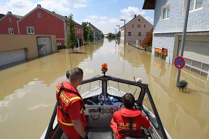 Auf einem Boot fahren Helfer des DLRG durch das überflutete Deggendorf.