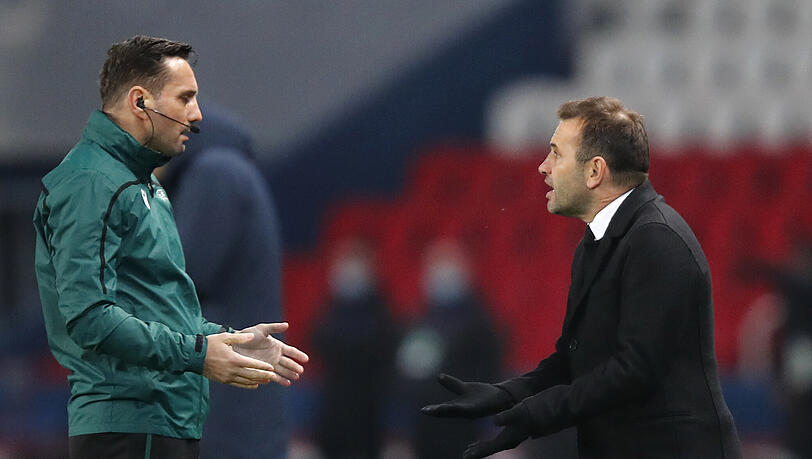 Okan Buruk (r), Trainer von Istanbul Basaksehir, spricht mit dem Vierten Offiziellen Sebastian Coltescu. Das nach einem Rassismusvorwurf gegen den Vierten Offiziellen abgebrochene Champions-League-Spiel wird wohl am Mittwoch wiederholt.
