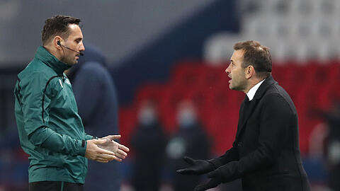 Okan Buruk (r), Trainer von Istanbul Basaksehir, spricht mit dem Vierten Offiziellen Sebastian Coltescu. Das nach einem Rassismusvorwurf gegen den Vierten Offiziellen abgebrochene Champions-League-Spiel wird wohl am Mittwoch wiederholt.