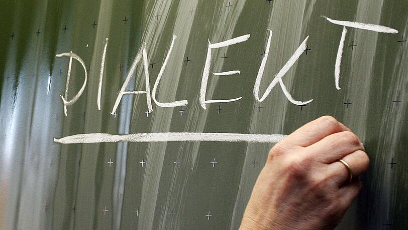 Das Wort "Dialekt" steht auf einer Tafel.