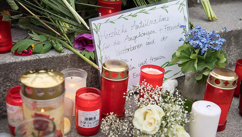 Blumen und Kerzen liegen am Bahnhof in Grafing um ein handgemaltes Schild. Bei einer Messerattacke waren am Dienstag drei Personen verletzt und ein Mann getötet worden. Blumen und Kerzen liegen am Bahnhof in Grafing um ein handgemaltes Schild. Bei einer Messerattacke waren am Dienstag drei Personen verletzt und ein Mann getötet worden.