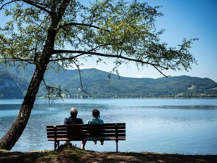 Ein Mann und eine Frau sitzen auf einer Bank am Kochlsee. Foto: picture alliance / Matthias Balk/dpa/Archivbild