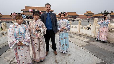 Markus Söder besucht die historische verbotene Stadt in der chinesischen Hauptstadt und steht neben Frauen in traditionellen Kostümen.