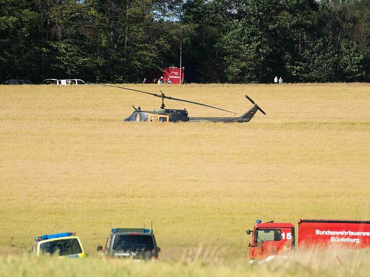 Einsatzfahrzeuge und ein Hubschrauber der Bundeswehr nahe der Absturzstelle.