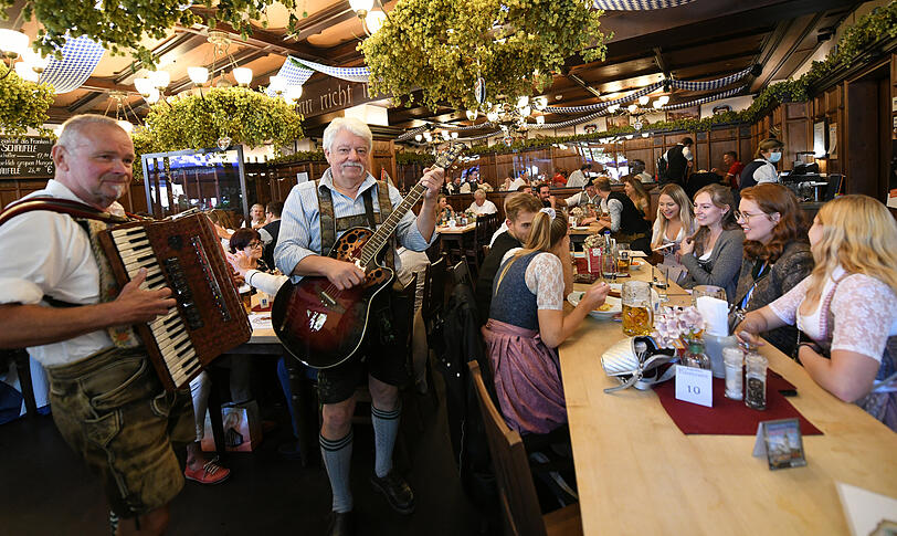 Gäste feiern bei Musik in einem Wirtshaus den Start der WirtshausWiesn 2021.