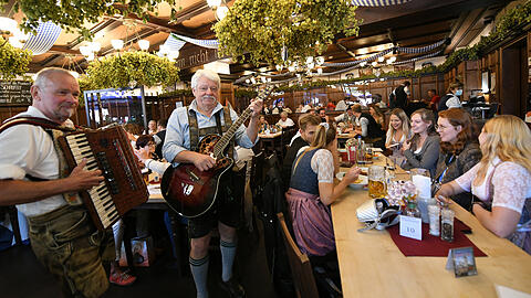 Gäste feiern bei Musik in einem Wirtshaus den Start der WirtshausWiesn 2021.