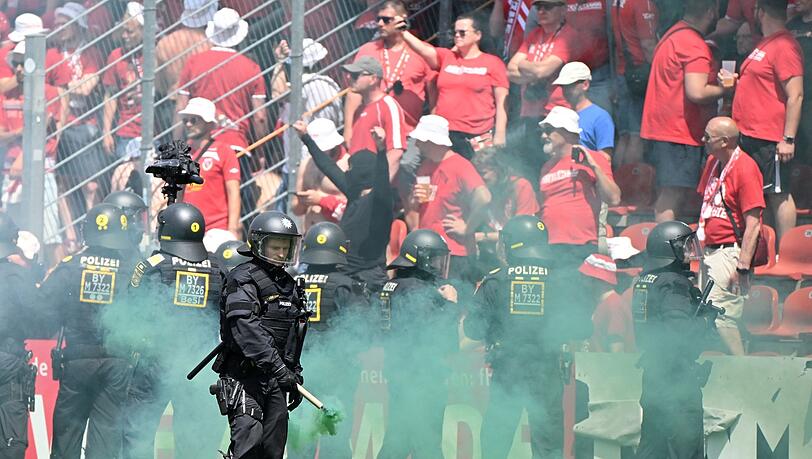 Ein Polizist entfernt während dem Spiel eine Rauchfackel vom Platz.