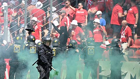 Ein Polizist entfernt während dem Spiel eine Rauchfackel vom Platz.