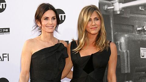 Courteney Cox und Jennifer Aniston Arm in Arm bei einer Veranstaltung.