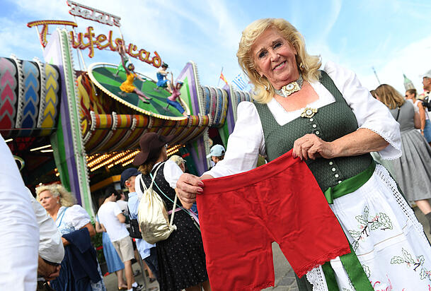 Die Betreiberin des Teufelsrades, Elisabeth "Lisi" Polaczy, steht mit einer Radlerhose vor dem Traditionsfahrgeschäft "Teufelsrad". Als Schutz vor Upskirting können sich Besucherinnen eine solche ausleihen. Die Betreiberin des Teufelsrades, Elisabeth "Lisi" Polaczy, steht mit einer Radlerhose vor dem Traditionsfahrgeschäft "Teufelsrad". Als Schutz vor Upskirting können sich Besucherinnen eine solche ausleihen.