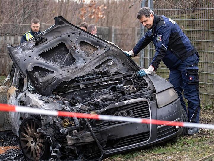 Brandermittler der Polizei untersuchen das ausgebrannte Fluchtfahrzeug.