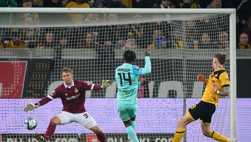 Münchens Abdenego Nankishi (M) trifft gegen Dynamos-Torwart Torwart Kevin Broll (l) und Kevin Ehlers.
