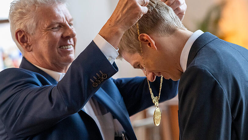 Sein Vorg&auml;nger Dieter Reiter h&auml;ngt dem neuen Oberb&uuml;rgermeister Dominik Krause die Amtskette um.