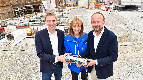 Oberb&uuml;rgermeister Dominik Krause (Gr&uuml;ne), Gabriele Jahn (Gesch&auml;ftsf&uuml;hrerin Personal, Immobilien und B&auml;der SWM), Bernhard Boeck (Gesch&auml;ftsbereichsleiter Immobilien SWM) mit der Zeitkapsel, die sie gleich im Grundstein versenken werden.