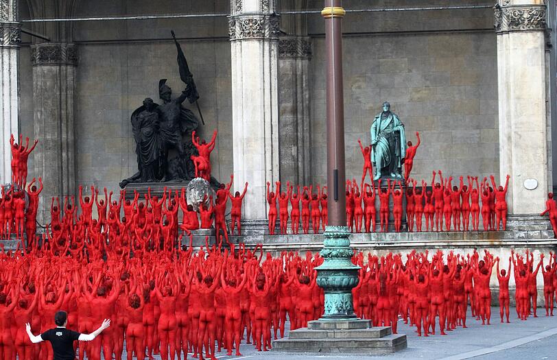 Star-Fotograf Spencer Tunick lässt zur Eröffnung der Opernfestspiele für seine Installation hunderte bunt angemalte Menschen durch München laufen. Das Highlight: Die rot-goldenen Teilnehmer stellen sich an Münchner Monumenten entlang der Ludwigstraße auf. Hier gibts die Bilder!