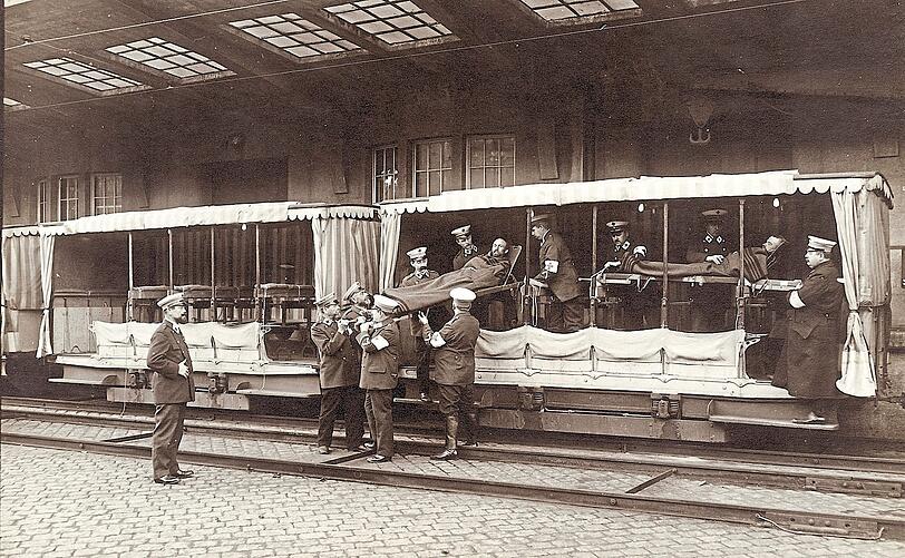 Rot-Kreuz-Lazarett auf Schienen: Zwei Verwundete werden aus offenen Waggons ausgeladen.