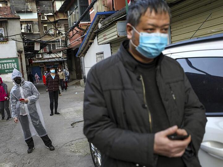 Menschen halten Abstand, während sie in Wuhan für Schweinefleisch anstehen.