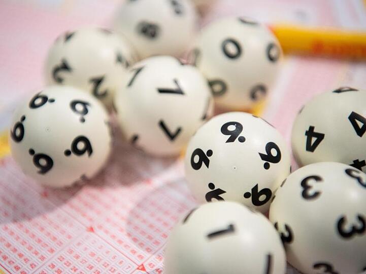 Lotto-Kugeln liegen auf einem Lottoschein. Foto: Tom Weller/dpa/Archivbild