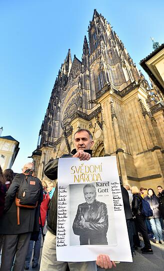 Ein Fan hält ein Poster mit handgeschriebenen Botschaften und einem Porträt des verstorbenen Sängers Karel Gott.