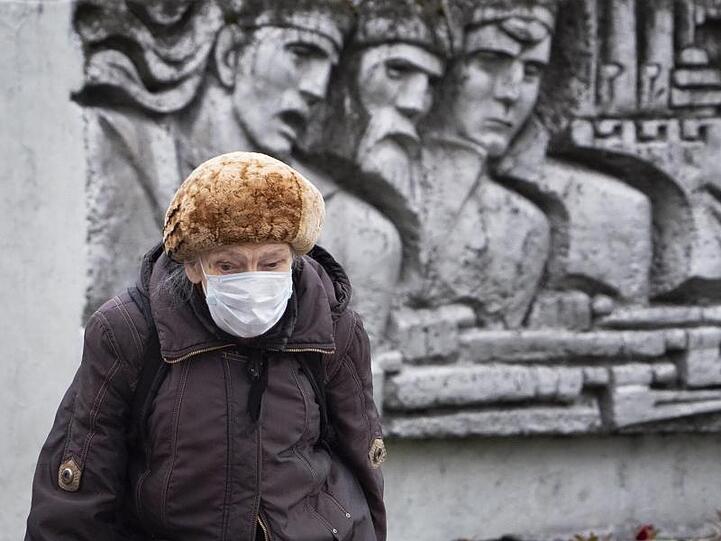 Eine ältere Frau in St. Petersburg vor einem Relief aus der Sowjetzeit.