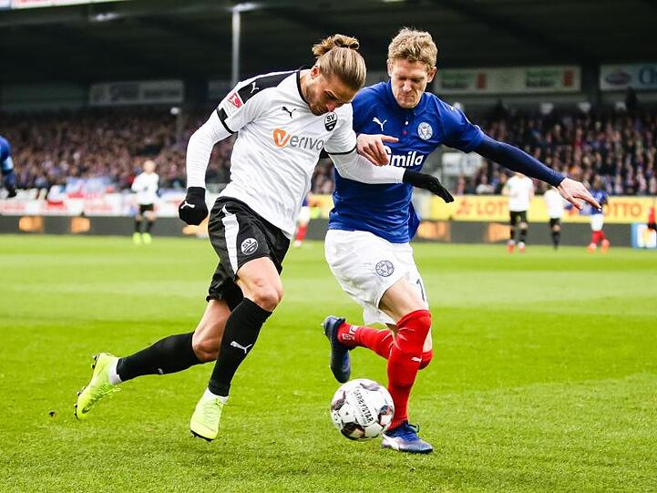 Sandhausens Rurik Gislason (l) und Johannes van den Bergh von Holstein Kiel kämpfen um den Ball.