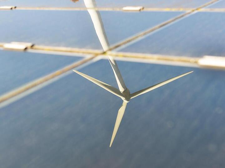 Ein Windrad spiegelt sich in einer Solaranlage. Foto: Uli Deck/Archivbild