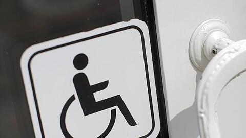 An einer Tür klebt ein Hinweisschild für Menschen mit Behinderung.