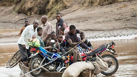 Nach dem Zyklon transportieren Männer in Malawi ihre geretteten Habseligkeiten mit einem Holzboot.