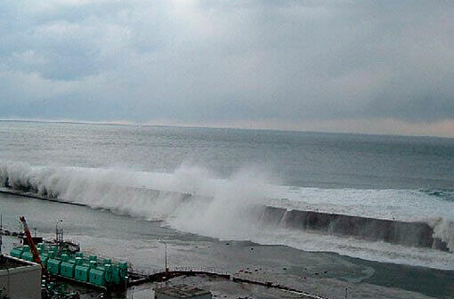 Mit voller Wucht rollt ein gigantischer Tsunami auf die Küste zu - dort, wo das Atomkraftwerk Fukushima steht. Die Wellen rollen über den Schutzwall.