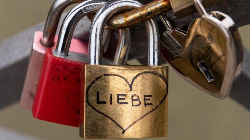Ein Liebesschloss mit der Aufschrift "Liebe" hängt am Geländer einer Brücke, die über die Isar führt. Foto: Peter Kneffel/dpa/Archivbild