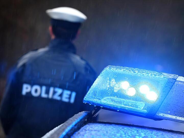 Ein Polizist steht vor einem Streifenwagen dessen Blaulicht aktiviert ist. Foto: Karl-Josef Hildenbrand/dpa/Archiv