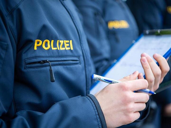 Angehende Streifenpolizisten notieren sich in einer Polizeischule etwas auf einer Notizmappe. Foto: Lino Mirgeler/dpa/Archivbild