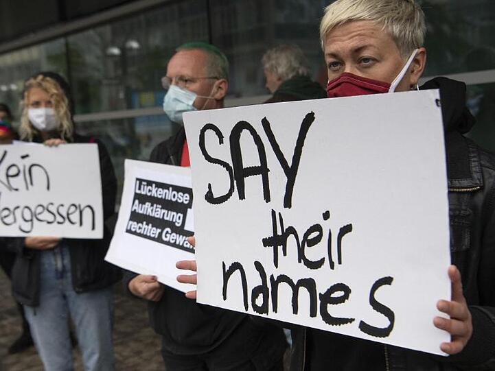 "Say their names" ("Nennt ihre Namen") steht auf einem Schild, mit dem eine Demonstrantin vor dem Gericht an die Opfer rechter Gewalt erinnert.
