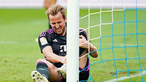 Harry Kane von München sitzt mit schmerzverzerrtem Gesicht auf dem Rasen. Er will gegen Dortmund spielen.