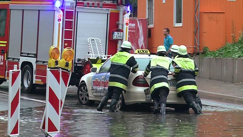 Feuerwehrleute schieben am Mittwochabend (20.06.2012) in München ein Taxi aus einer überfluteten Unterführung. Unwetter und Starkregen hatten in Südbayern für zahlreiche überflutete Keller und vollgelaufene Unterführungen gesorgt.