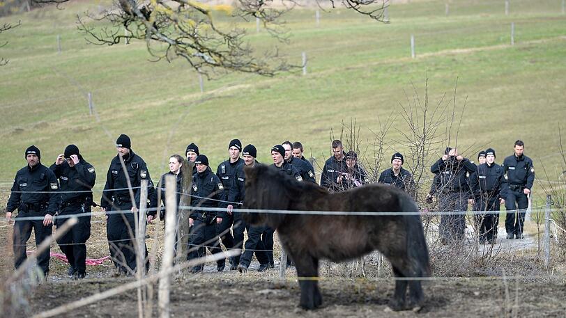 Polizisten untersuchen den Feldweg hinter dem Haus.