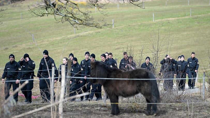 Polizisten untersuchen den Feldweg hinter dem Haus. Polizisten untersuchen den Feldweg hinter dem Haus.