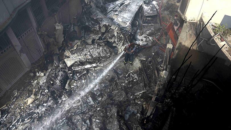 Ein Feuerwehrmann versucht das Feuer an der Absturzstelle zu löschen: Ein Flugzeug mit rund 100 Passagieren an Bord ist im Süden Pakistans abgestürzt.