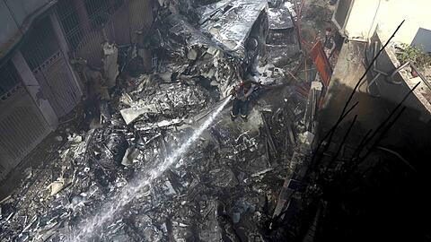 Ein Feuerwehrmann versucht das Feuer an der Absturzstelle zu löschen: Ein Flugzeug mit rund 100 Passagieren an Bord ist im Süden Pakistans abgestürzt.