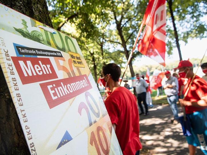 Teilnehmer einer Demonstration der IG BAU stehen auf der Theresienwiese. Foto: Matthias Balk/dpa
