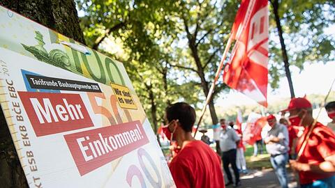 Teilnehmer einer Demonstration der IG BAU stehen auf der Theresienwiese. Foto: Matthias Balk/dpa