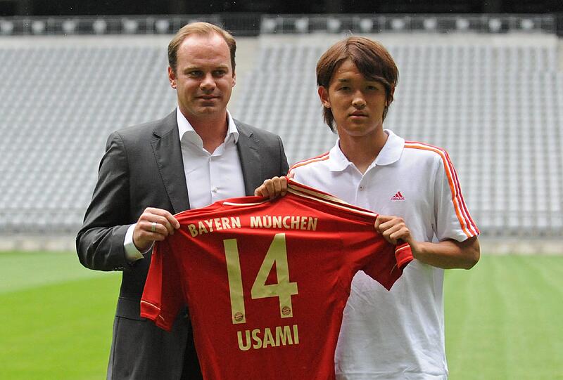 Sportdirektor Christian Nerlinger (l) vom Fußball-Bundesligisten FC Bayern München posiert am Montag in der Allianz Arena in München mit dem japanischen Fußballer Takashi Usami und dessen Trikot mit der Rückennummer 14.