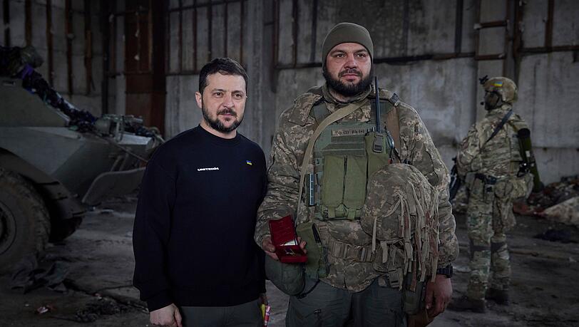 Wolodymyr Selenskyj steht neben einem Soldat anlässlich einer Verleihungszeremonie in einer Stellung in der Nähe von Bachmut.
