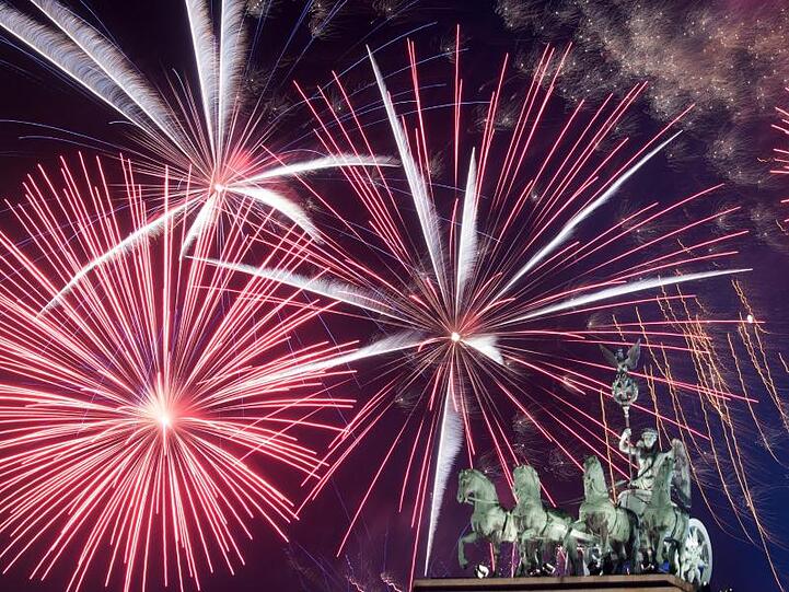 Ein Feuerwerk ist hinter dem Brandenburger Tor zu sehen. Foto: Ralf Hirschberger/dpa/Archiv