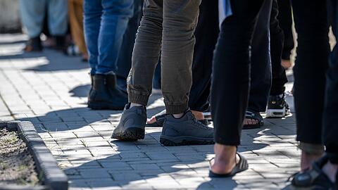 Flüchtlinge stehen in einer Erstaufnahme-Einrichtung in einer Schlange (Symbolbild). Der Stadtrat von Burg fordert im Brief an Kanzler Scholz unter anderem eine Rückführung abgelehnter Asylbewerber und eine Erweiterung der sicheren Herkunftsländer.