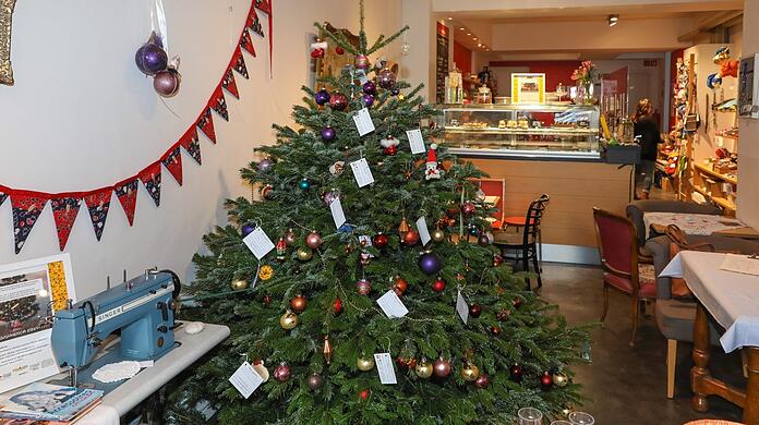Eine liebevoll bestückte Kuchentheke und gemütliches Café-Ambiente umgeben den Wunschbaum im Nähwerk.