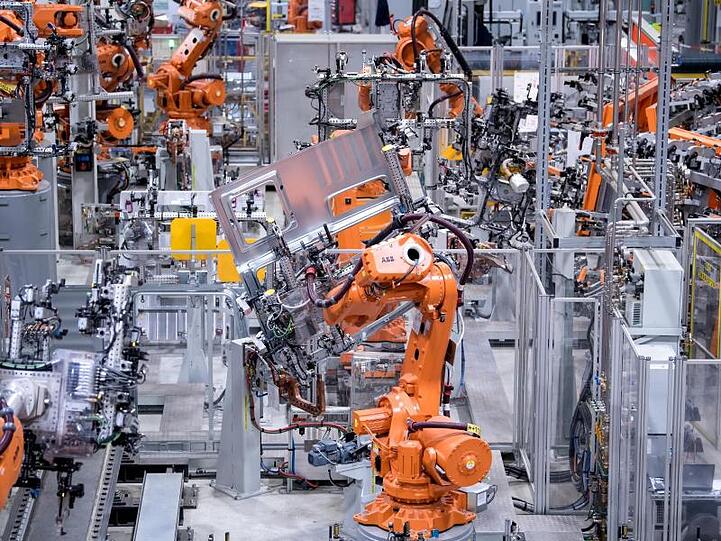 Roboter von ABB arbeiten bei MAN Truck & Bus in einer Werkshalle an Seitenwänden von Fahrerkabinen. Foto: Sven Hoppe/dpa/Archivbild